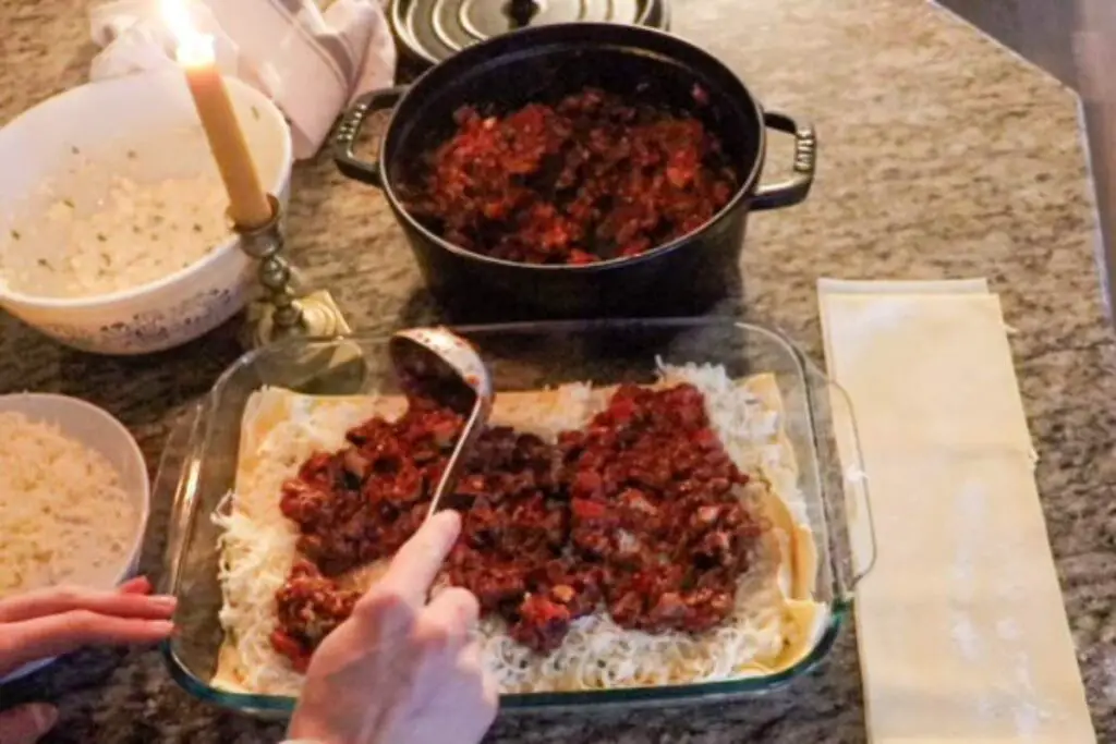 Scooping sauce into a lasagna