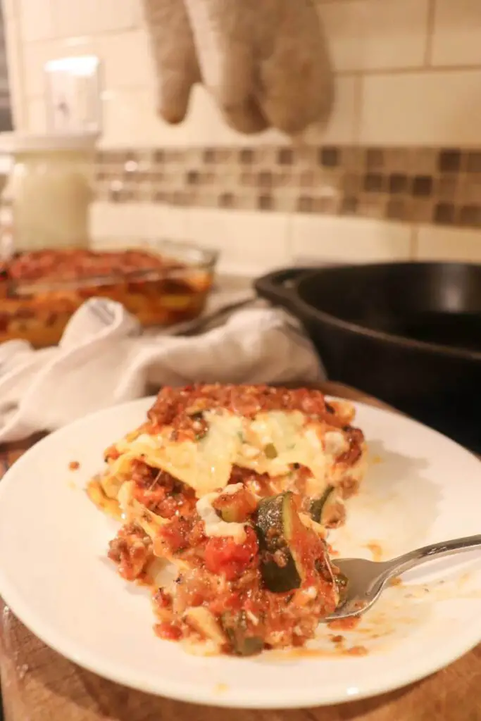 lasagna on a plate with a fork scooping a bite out of it