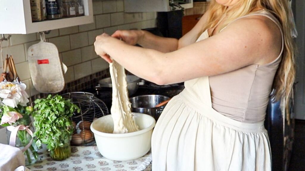 Stretching sourdough dough during the preparation process in a vintage-style kitchen.