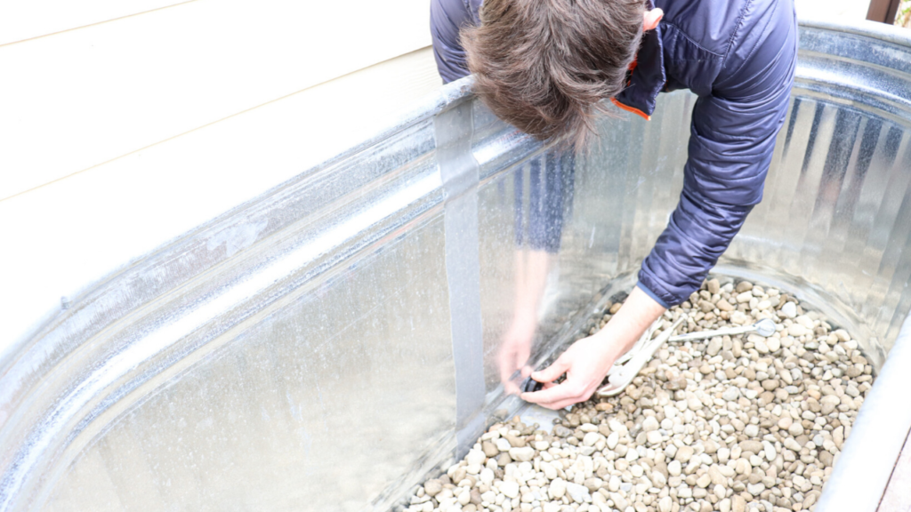 stopping the built-in drainage hole in the galvanized horse trough planter box on cedar wood stand