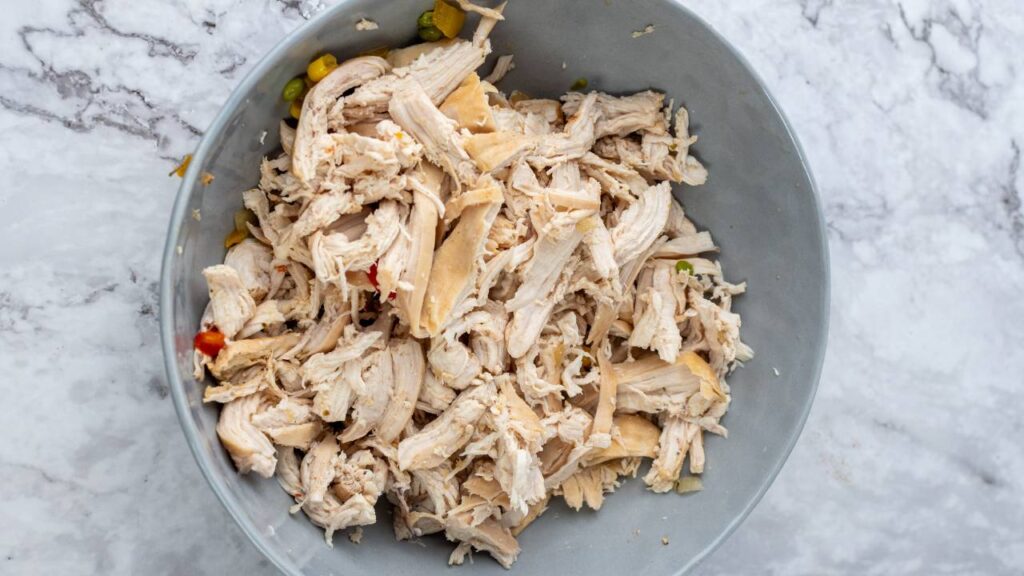 Shredded cooked chicken in a bowl ready to be added to the soup.