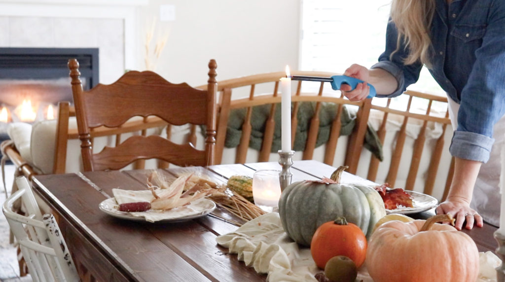 girl lighting a candle at the fall table scape