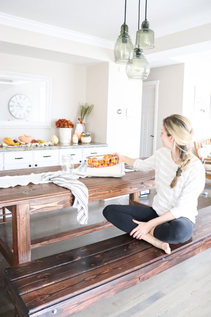 girl sitting at farmhouse table with a box of oranges