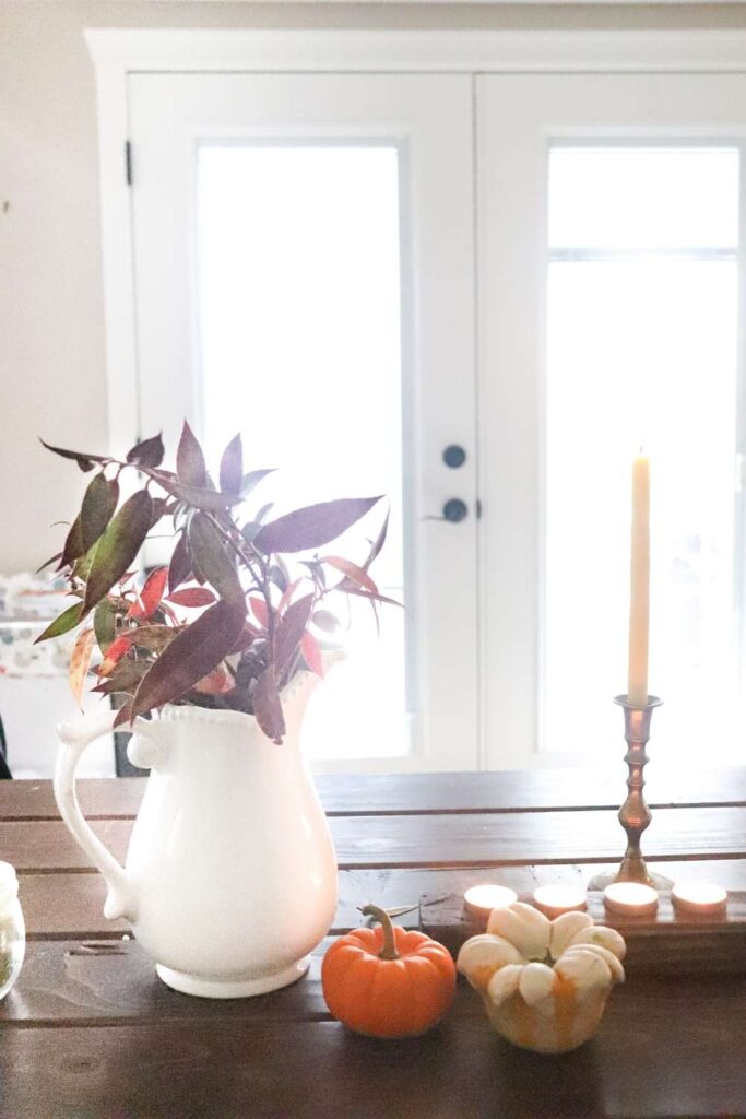 candles, pumpkins, and greenery on the dining table