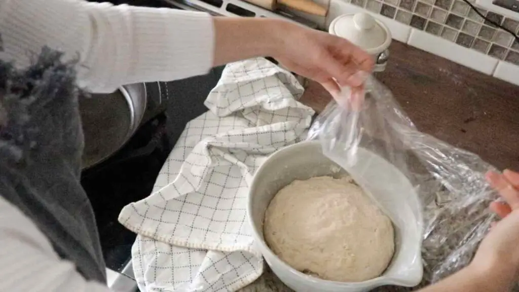 uncovering the bagel dough in the morning
