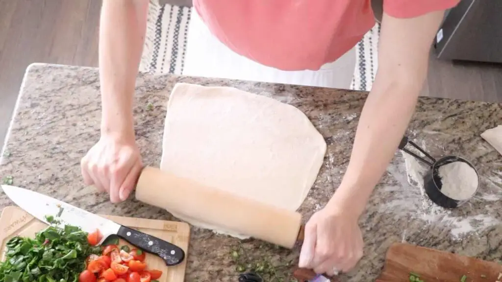 woman rolling out sourdough pizza crust