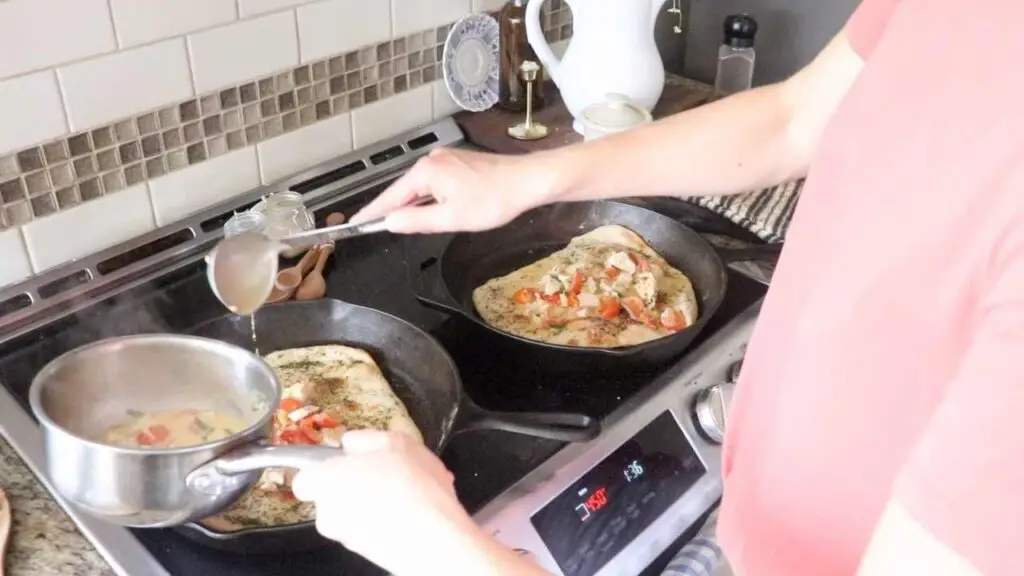 woman adding pizza toppings to sourdough pizza crust on cast iron skillets