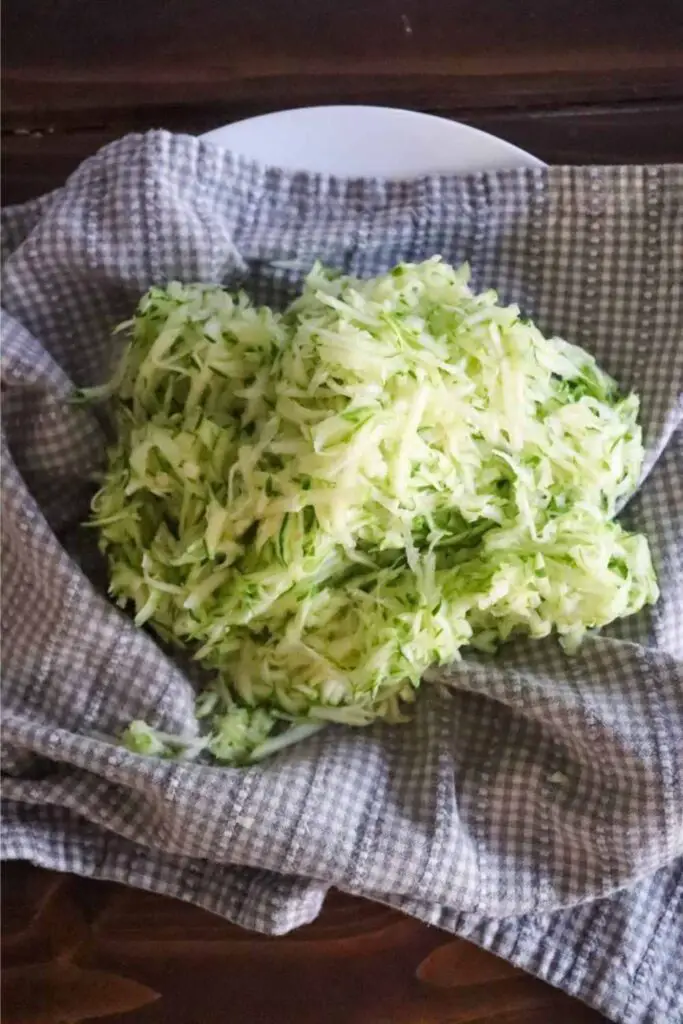 freshly grated and strained zucchini on a checked towel