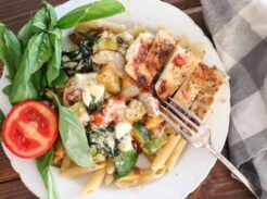 creamy basil chicken pasta in a white dish with garnish of fresh basil and tomato