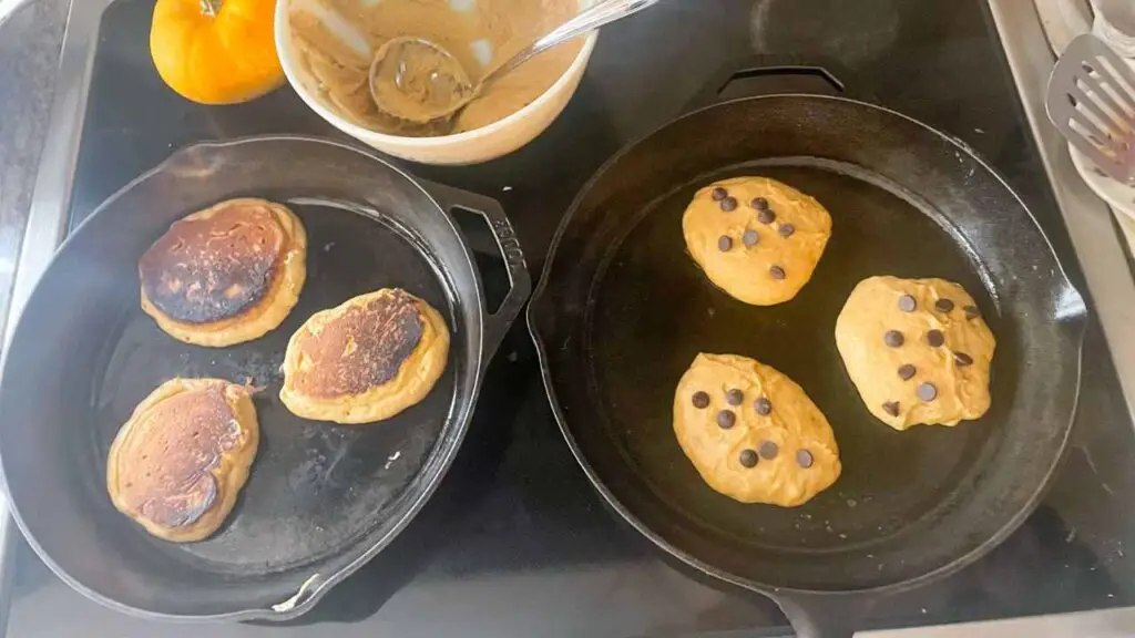 fluffy sourdough discard pumpkin pancakes cooking in cast iron skillets