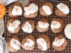 iced pumpkin cookies with sourdough discard and cream cheese frosting on a cooling rack on top of a farmhouse table