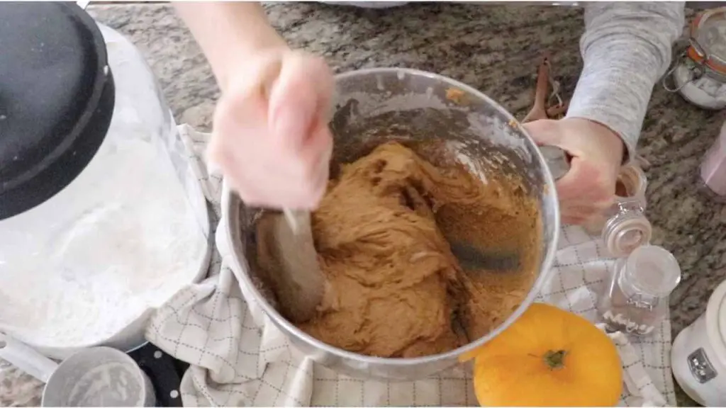 mixing batter for pumpkin cookies in the bowl of a stand mixer