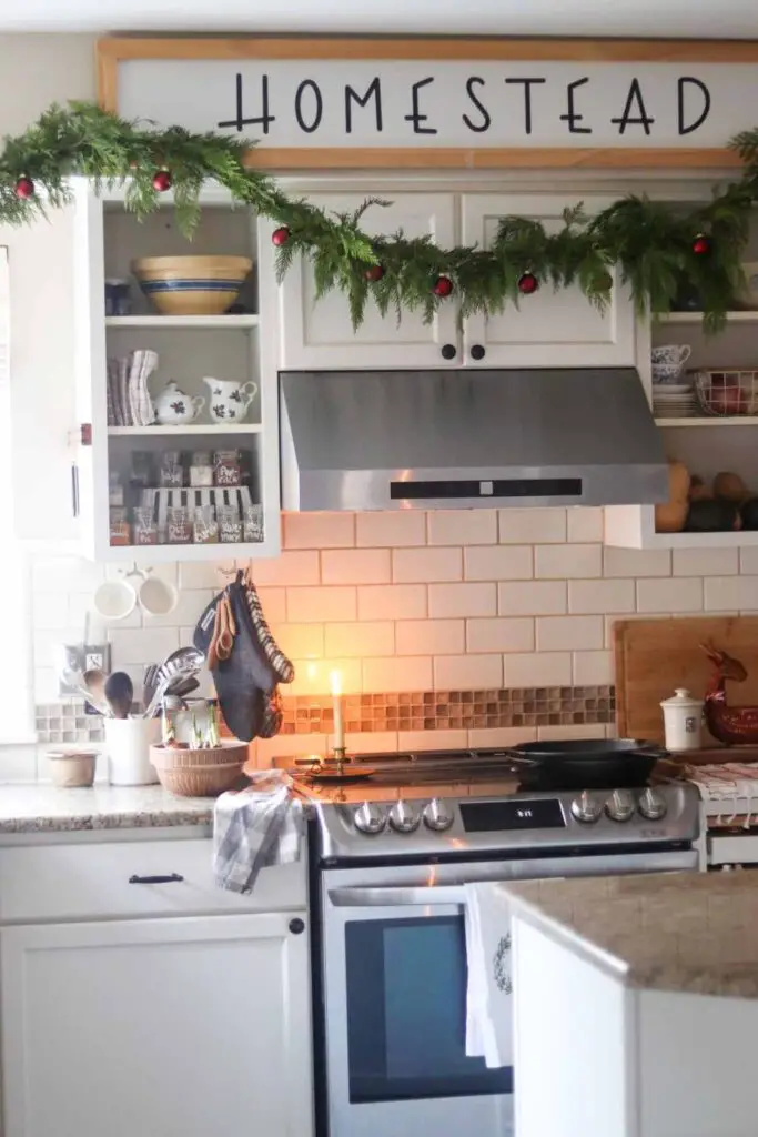 farmhouse kitchen decorated for Christmas with garland and red ornaments