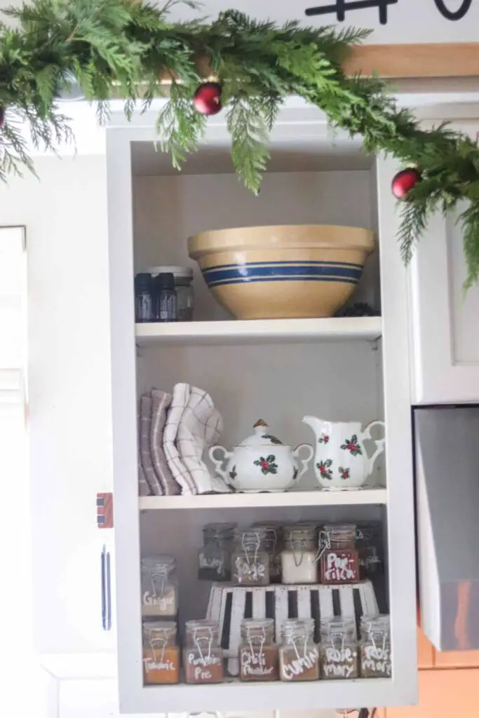 open shelving in kitchen decorated with vintage Christmas sugar and cream set, with fresh garland and red ornaments