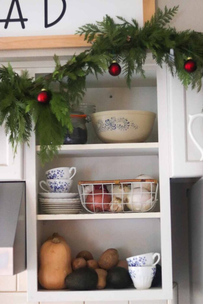 open shelving in kitchen, with fresh garland and red ornaments