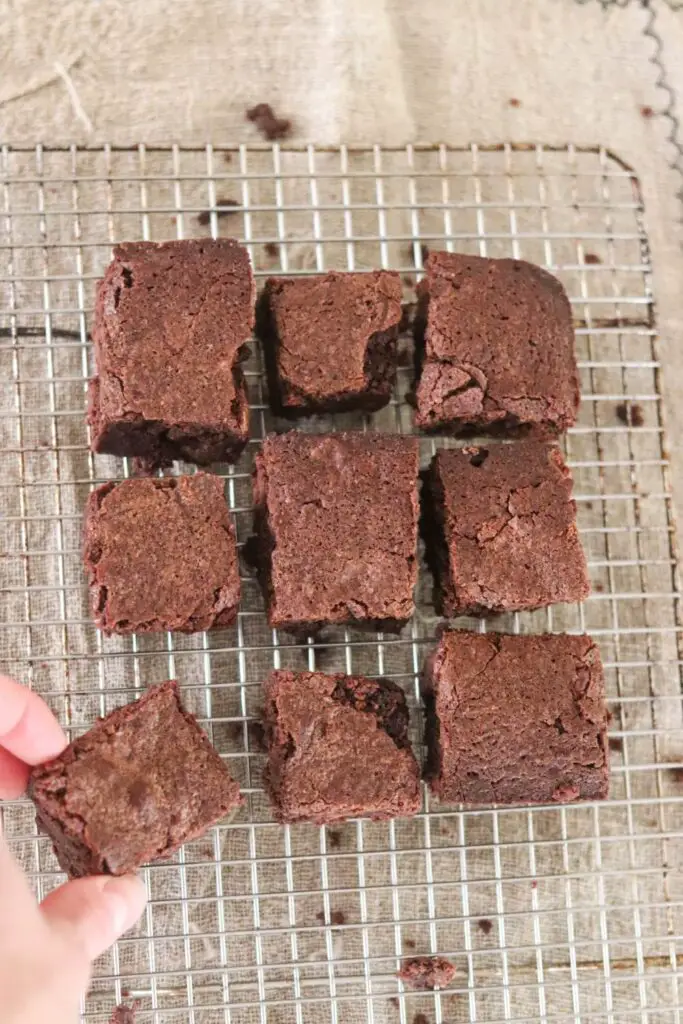 Einkorn brownies sitting on a cooling rack with a hand grabbing one.