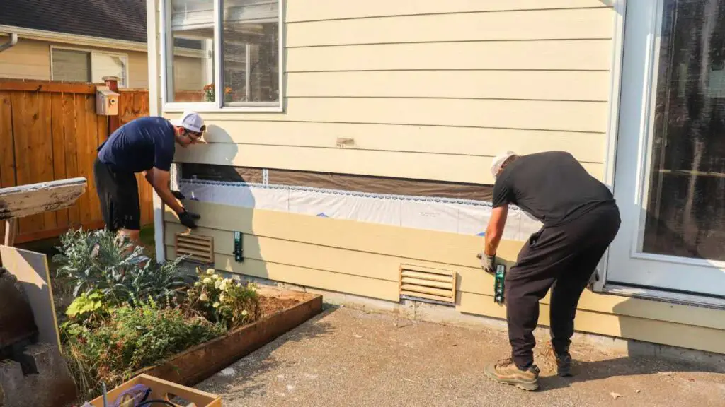 two men adding a new piece of hardie board siding to a house