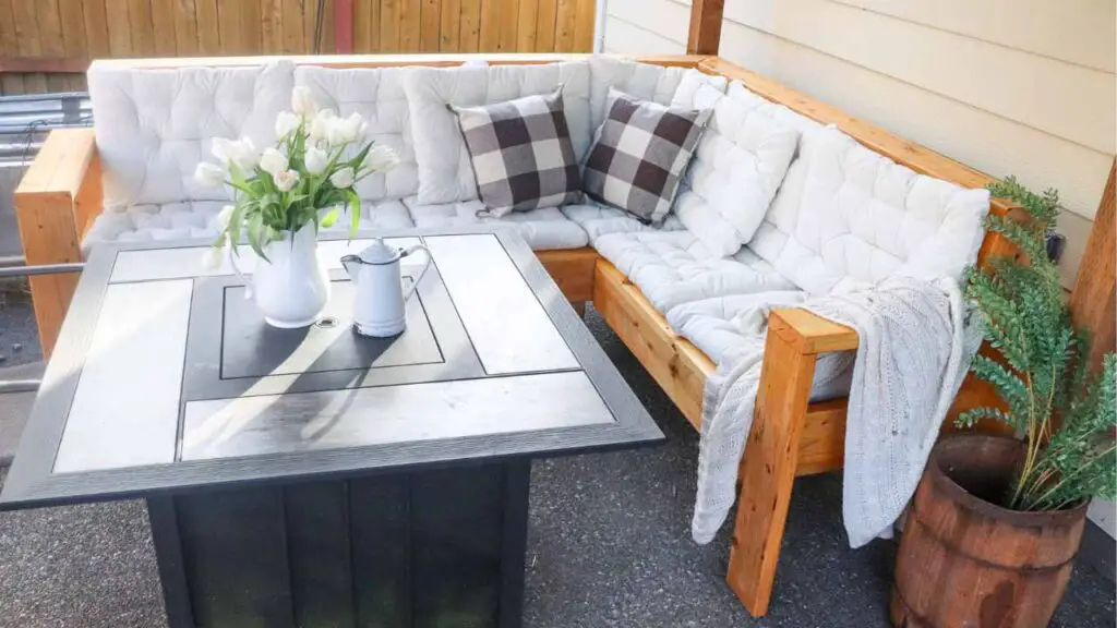 DIY outdoor sectional couch with white tufted cushions and buffalo check throw pillows with table fire pit with rustic decor accents