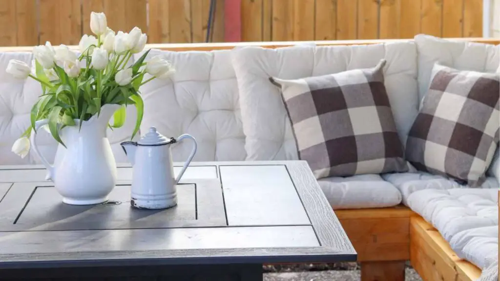 DIY outdoor sectional couch with white tufted cushions and buffalo check throw pillows, with fire pit table with white tulips and pitchers