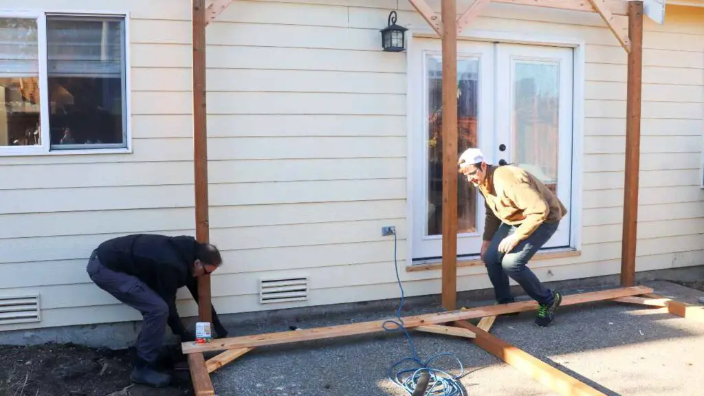 two men building a DIY freestanding patio cover