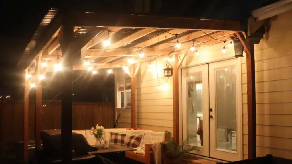 beautiful DIY free standing patio cover at night with string lights