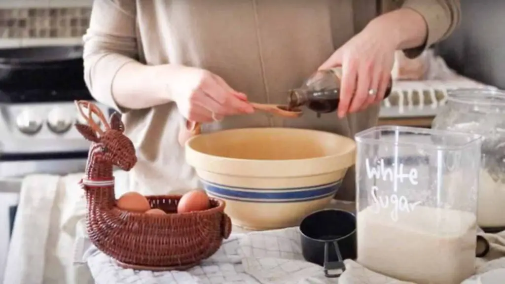 adding vanilla to a mixing bowl with ingredients to make chocolate brownies