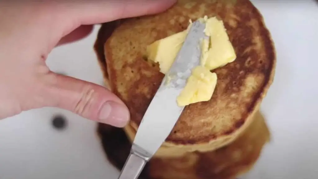adding a pat of butter to a stack of warm sourdough pumpkin pancakes