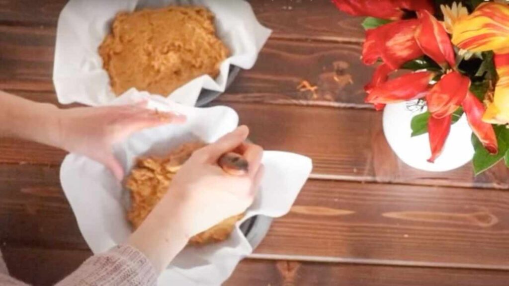 pour batter into parchment lined round baking pans on a farmhouse table with a bouquet of flowers