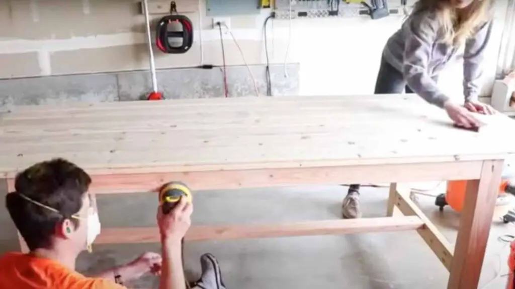 a couple works hard sanding a DIY farmhouse dining table