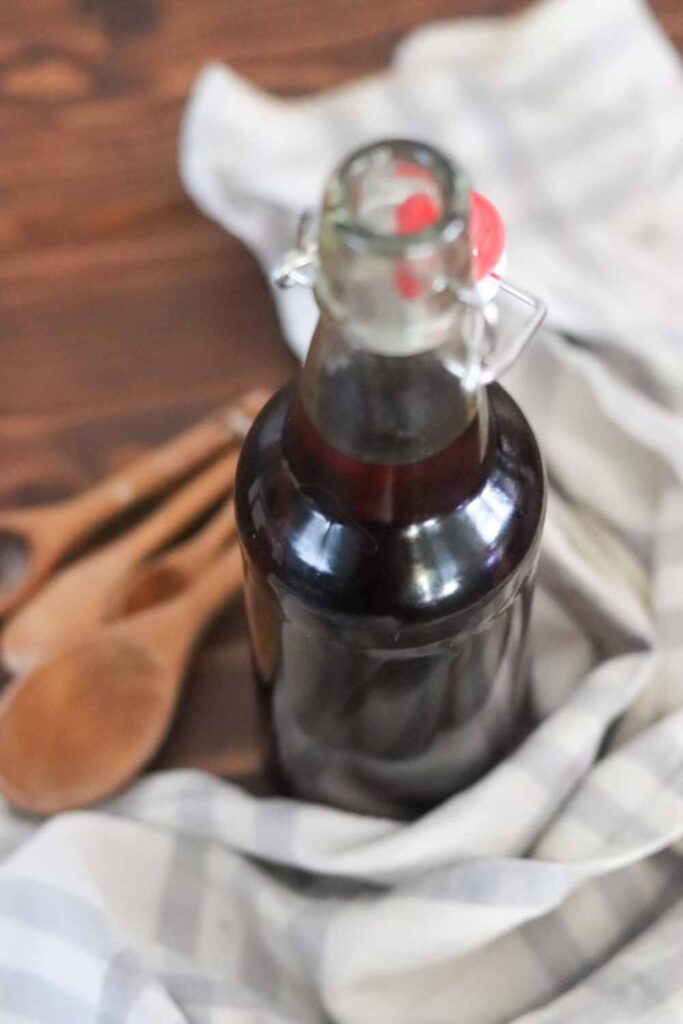 Glass bottle of homemade vanilla extract on a farmhouse table