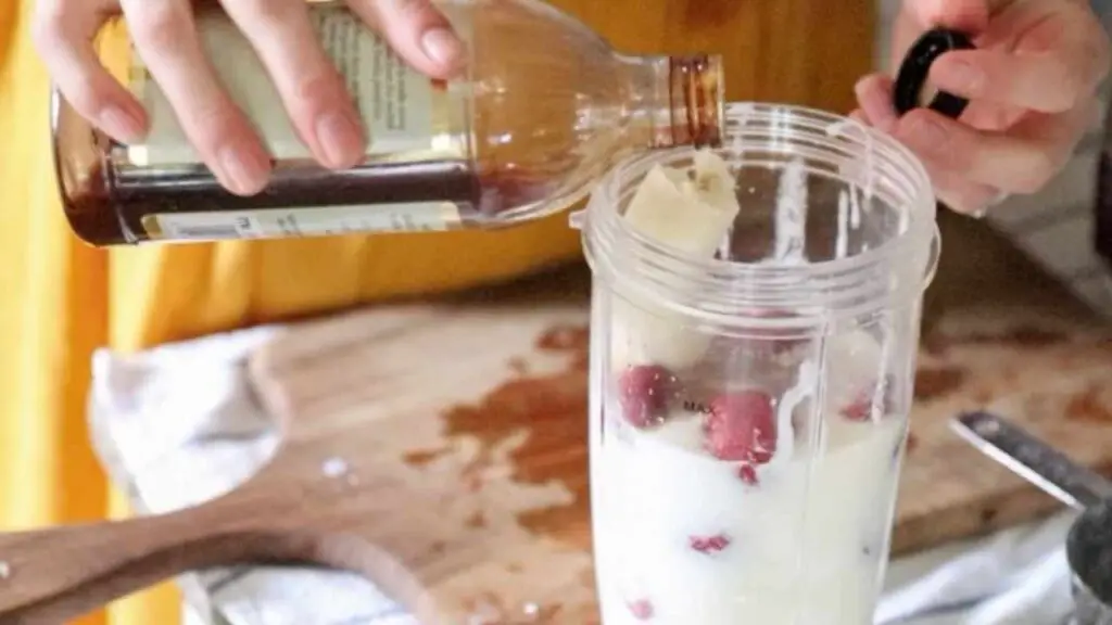 adding vanilla to a nutribullet with other ingredients for strawberry cream kefir popsicles