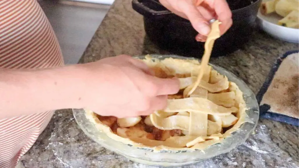 placing strips of einkorn sourdough pie crust dough on a pie to make lattice crust