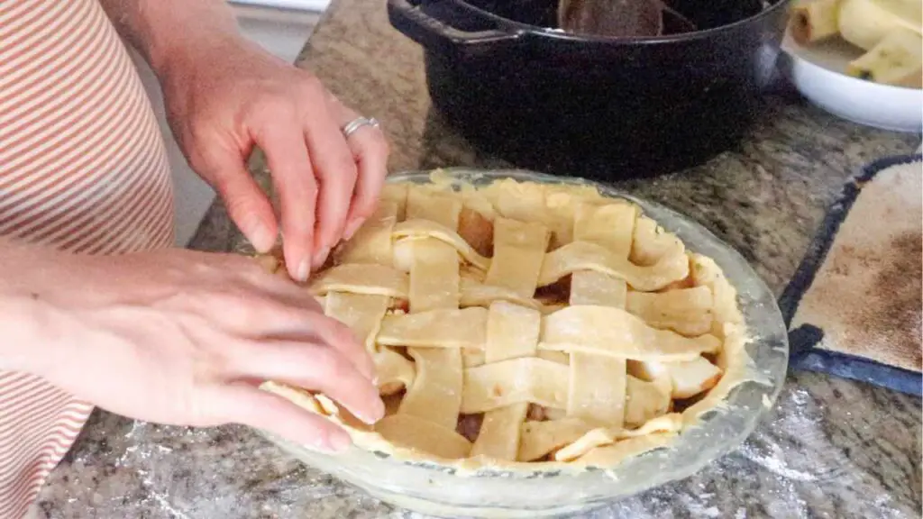 placing strips of einkorn sourdough pie crust dough on a pie to make lattice crust