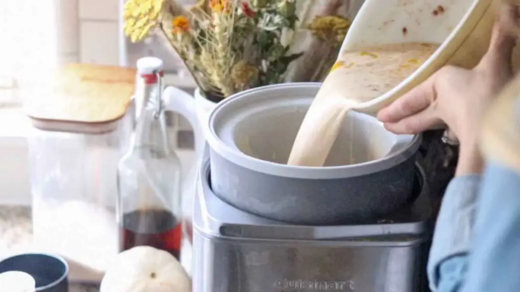 pouring homemade pumpkin ice cream mixture into an ice cream machine