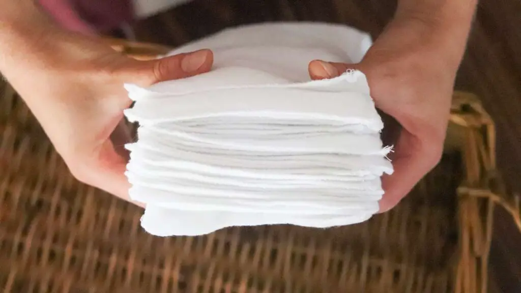 two hands holding a stack of baby wipes