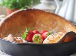 A dutch baby pancake in a skillet with fresh strawberries on top