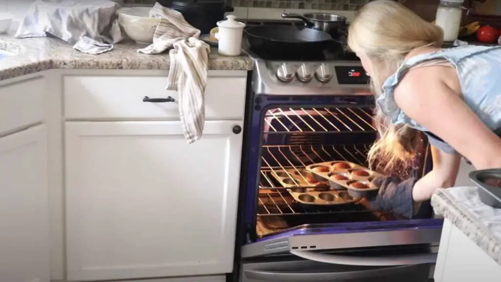 placing a muffin tin full of chocolate muffin batter into an oven