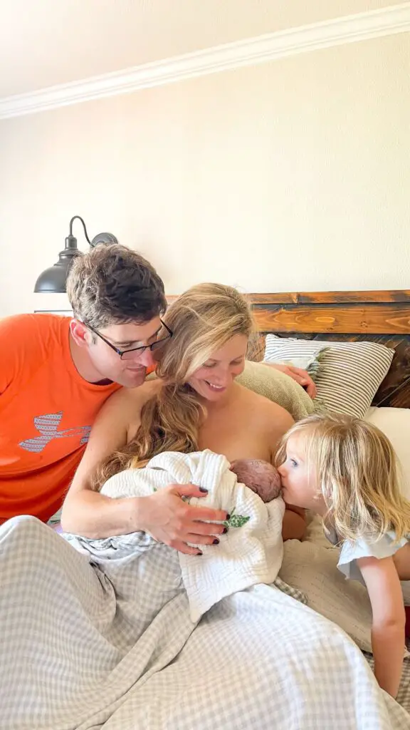 family of 4 sitting in bed after the birth of a baby