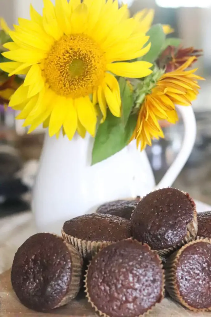 a plate of chocolate muffins with sunflowers in the background