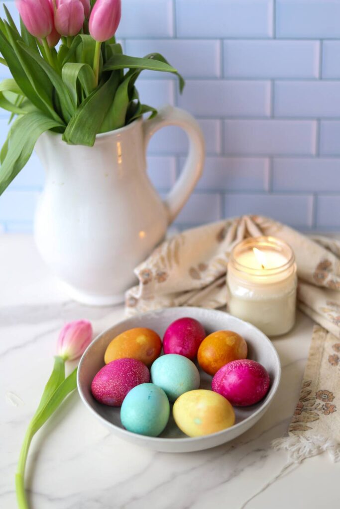 Bowl of naturally dyed Easter eggs with candle and kitchen decor