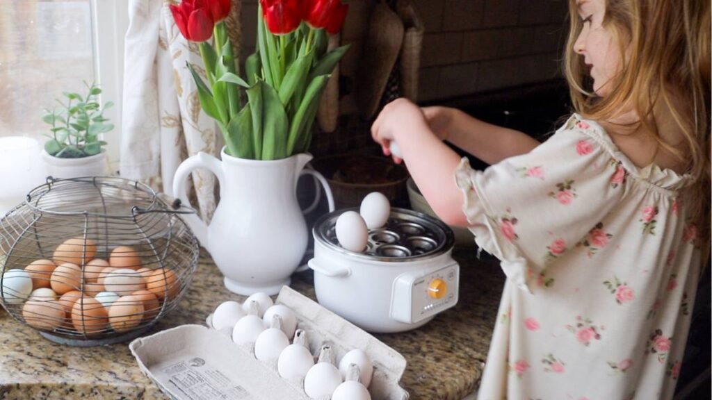 Child placing eggs into a countertop egg cooker