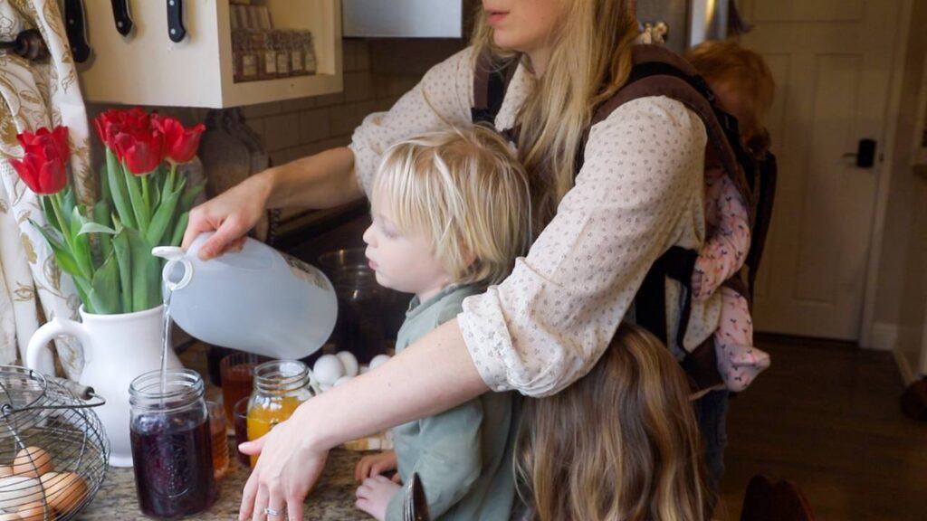 Mom pouring liquid into jars while kids watch during egg dyeing