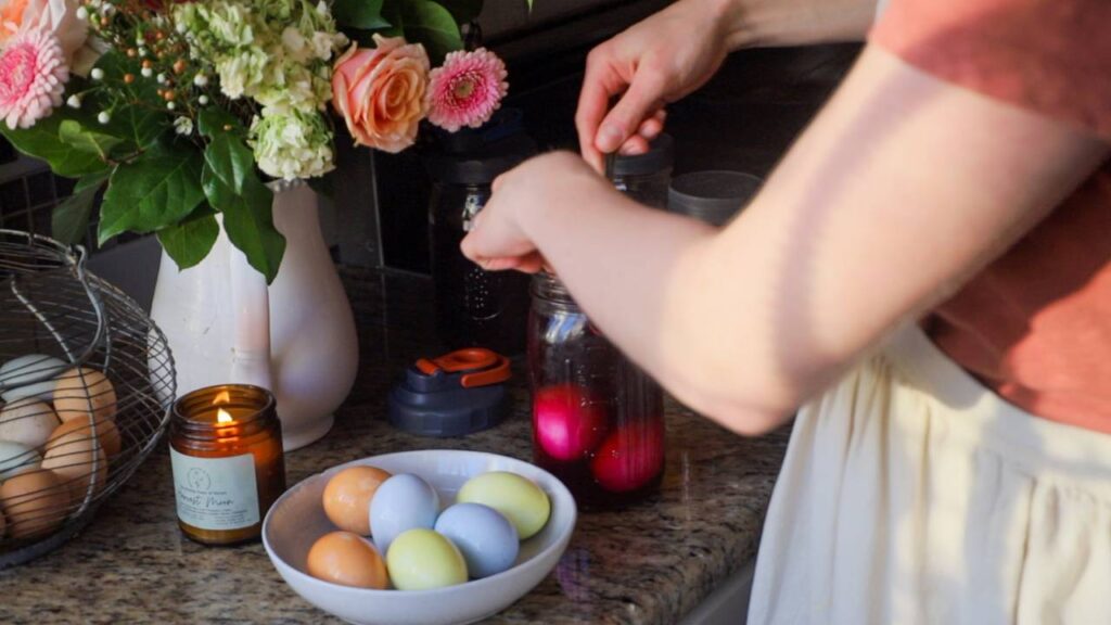 Eggs soaking in natural dye in jars on a kitchen counter