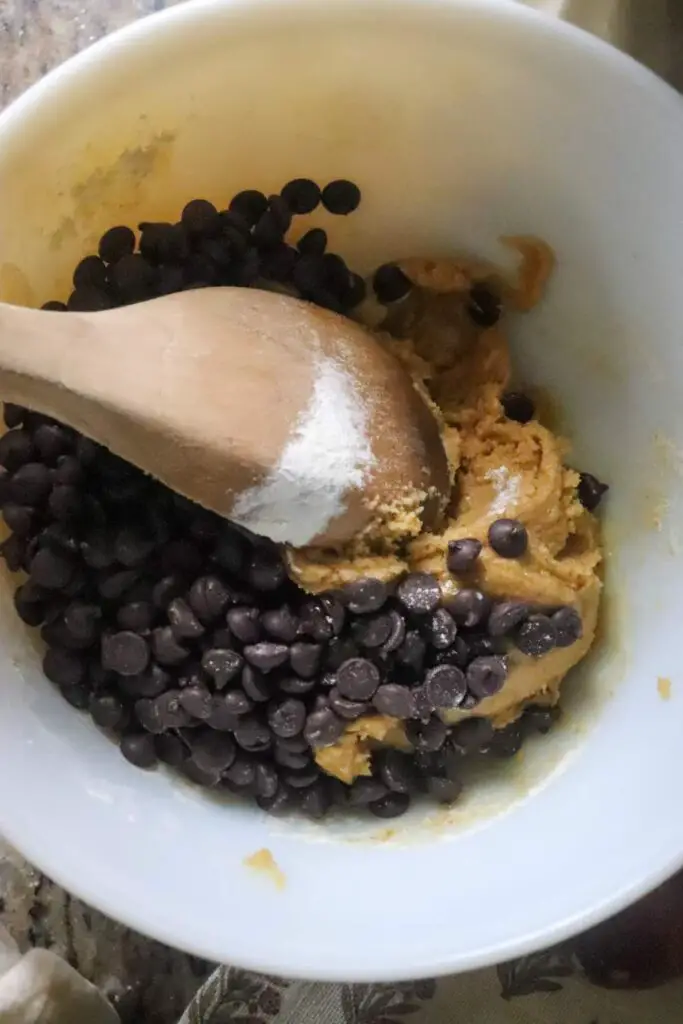 Chocolate chip cookie dough being stirred with a spoon.