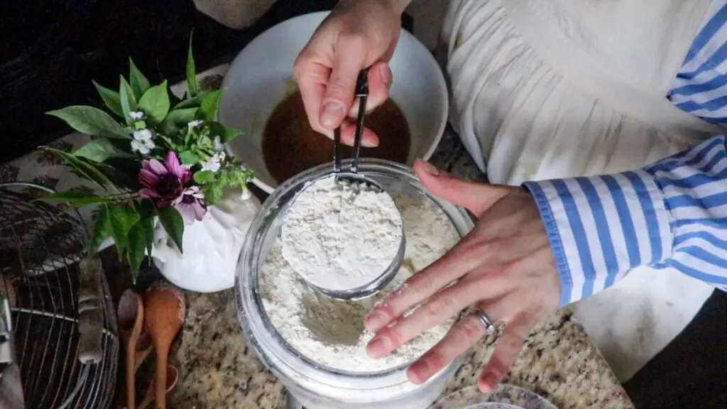 a woman adding einkorn flour to the cookie mixture