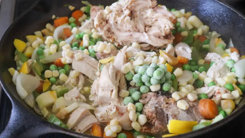 Veggies and chicken in a cast iron skillet, not yet sauteed. 