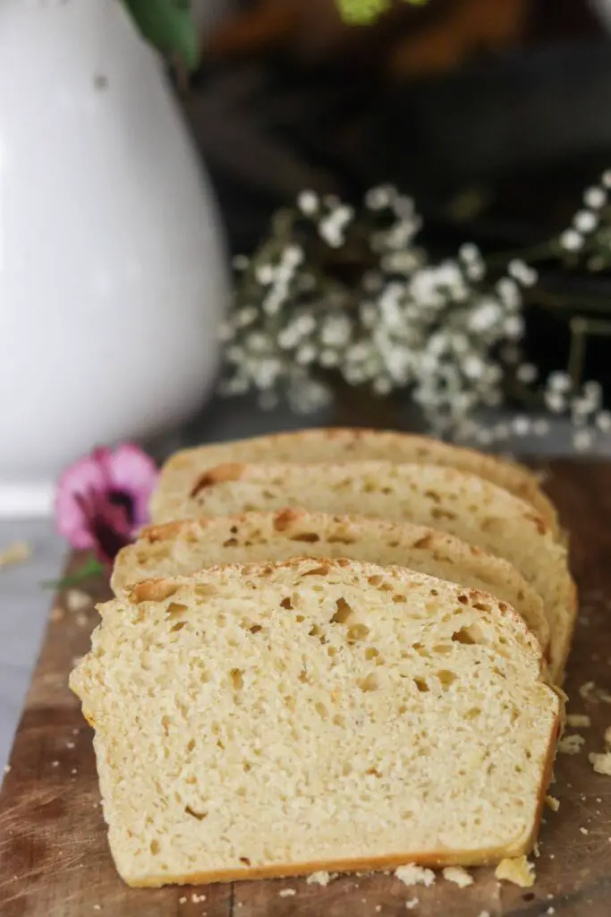 A sliced loaf of einkorn sourdough sandwich bread with fresh flowers.