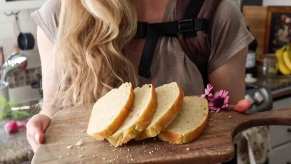 Alexa holding a wooden cutting board with freshly sliced einkorn sourdough sandwich bread on it. 