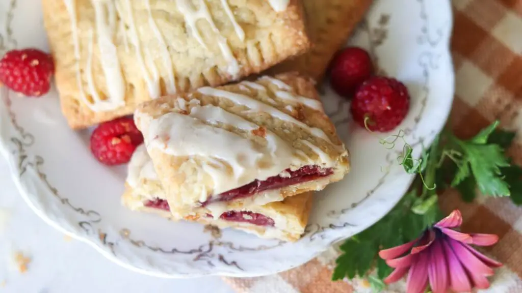 Looking down on a plate of homemade sourdough pop tarts with fresh raspberries and flowers around it.