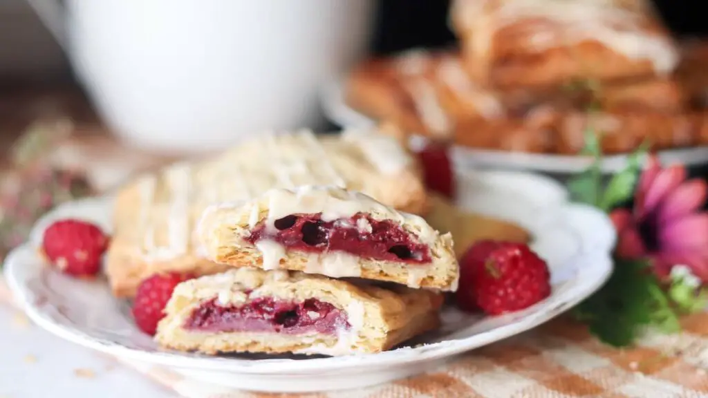 A homemade raspberry pop tart cut in half on a plate.